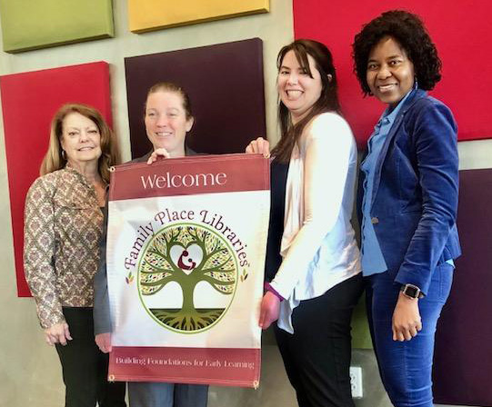 Members of the Bryan + College Station Public Library System staff show the new banner designating Larry J. Ringer Library as a Family Place Library.