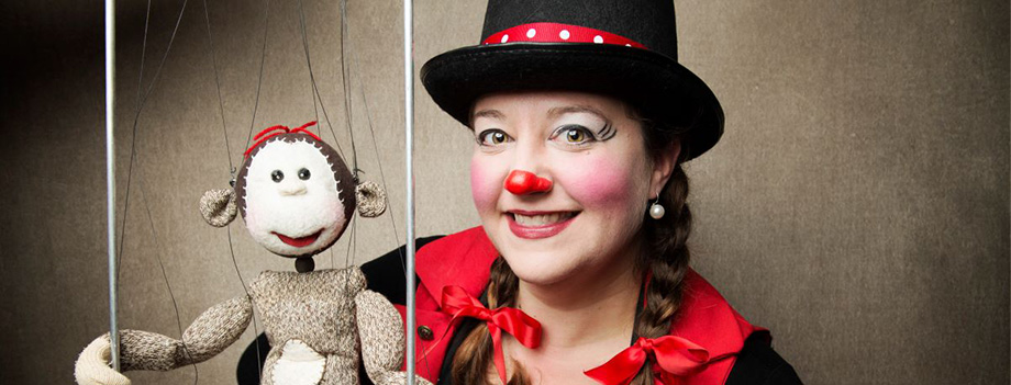 Cast member dressed like a clown posing with a monkey sock puppet