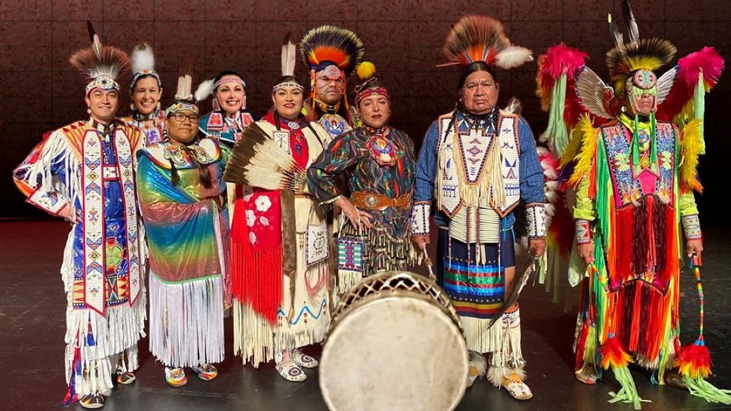 The group Great Promise for American Indians, dressed in traditional clothing. A large drum sits in front of the group.